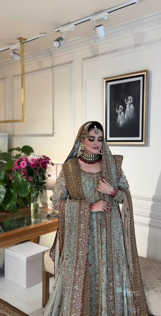 This beautiful ensemble features a richly detailed chiffon kurta adorned with delicate dabka and sitara hand embroidery. The premium malai‑lined kurta provides comfort while enhancing the luxurious feel, and the traditional gharara adds graceful volume and movement to your silhouette