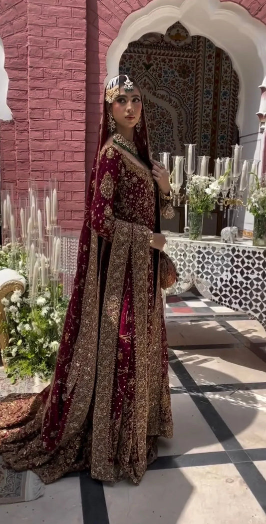 Haris Shakeel Ishq Series bridal ensemble in deep romantic maroon featuring intricate adda work and hand embellishment with fine dabka and handworked motifs spread generously across the shirt, sleeves, and flowing lehenga with richly embellished borders, paired with a heavily worked dupatta with ornate edging, perfect for brides seeking classic sophistication and traditional grandeur.