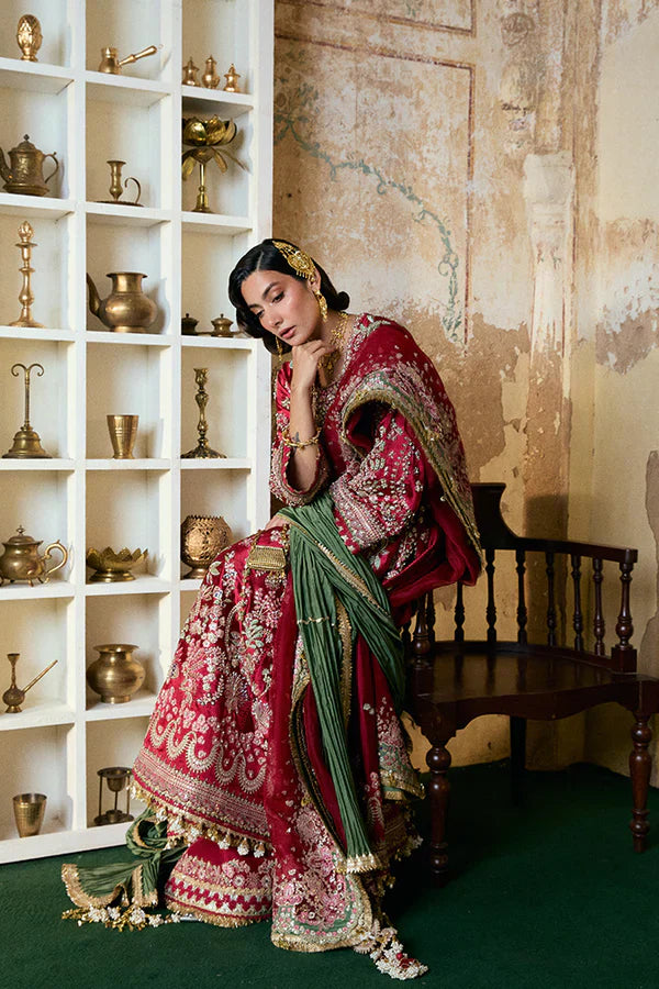 Suffuse Afsanae red bridal maxi dress featuring intricate hand embroidery with detailed floral and botanical motifs in gold and silver threadwork, paired with a heavily embellished red dupatta with ornate borders and a contrasting deep green velvet shawl, perfect for nikah, barat, reception, and formal wedding events.