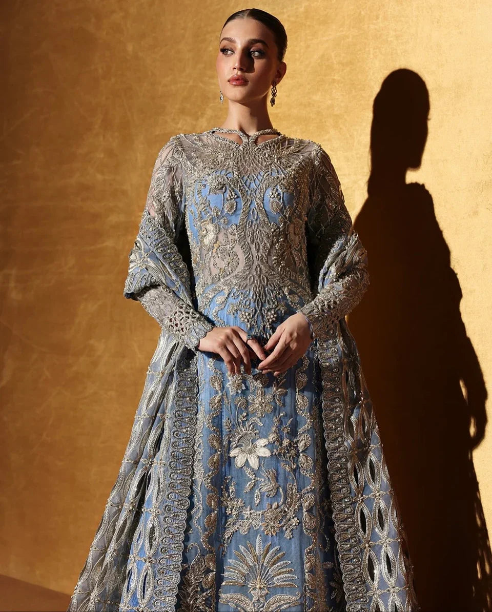 Soraya inspired Seralyn luxury formal ensemble in a soft ethereal pastel palette with subtle warm undertones featuring intricate hand embellishments and shimmering accents on a flowing silhouette with a richly worked bodice and embellished flare, paired with a coordinated dupatta with elegant borders, perfect for weddings and formal celebrations.