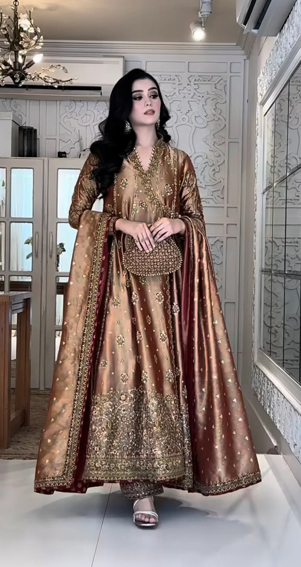 Haris Shakeel Aswad bronze-gold formal ensemble featuring intricate hand embellishments with detailed floral motifs, delicate sequins, and refined accents on an elongated silhouette with a heavily worked hemline, perfect for weddings, receptions, formal dinners, and festive celebrations.