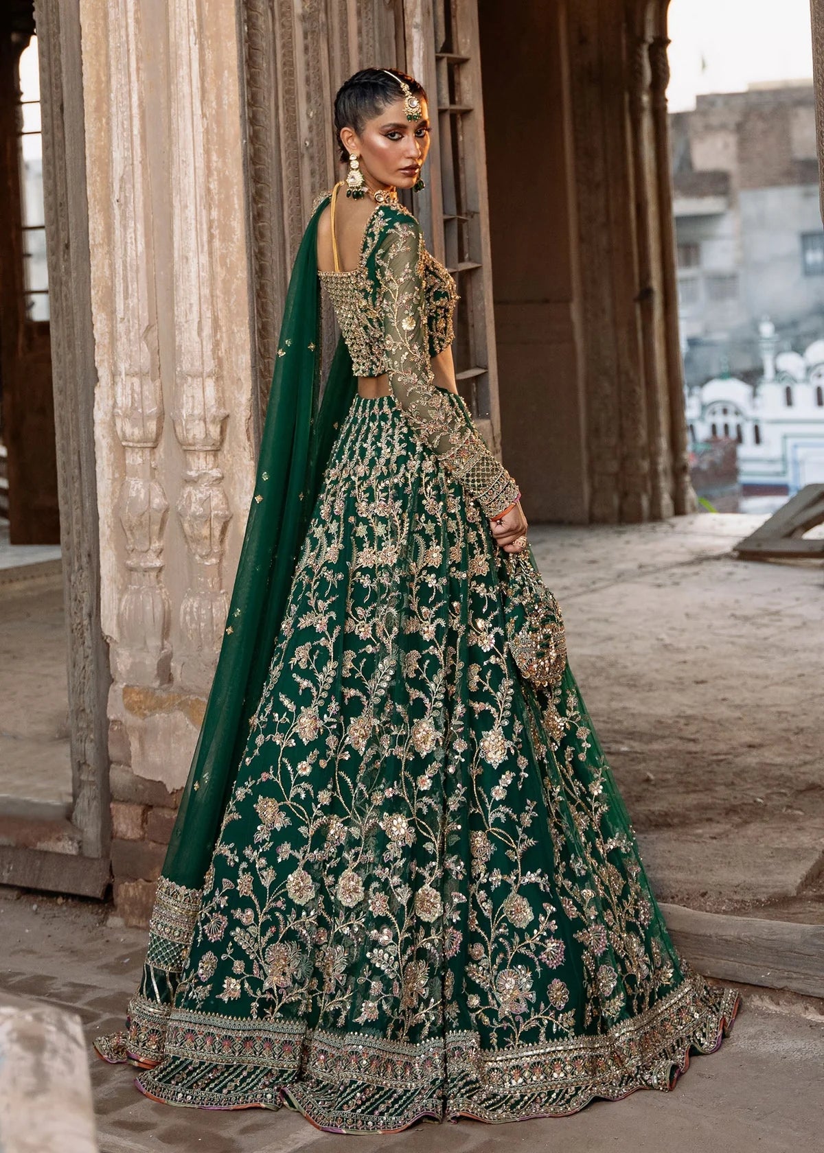  Kanwal Malik Sukhan bottle green net lehenga choli featuring an intricately embellished choli and flowing lehenga with a floral jaal design in vibrant orange and pink accents, enhanced with gold, gotta, and silver embellishments, complete with a matching net dupatta with an embellished border, perfect for weddings and festive occasions.