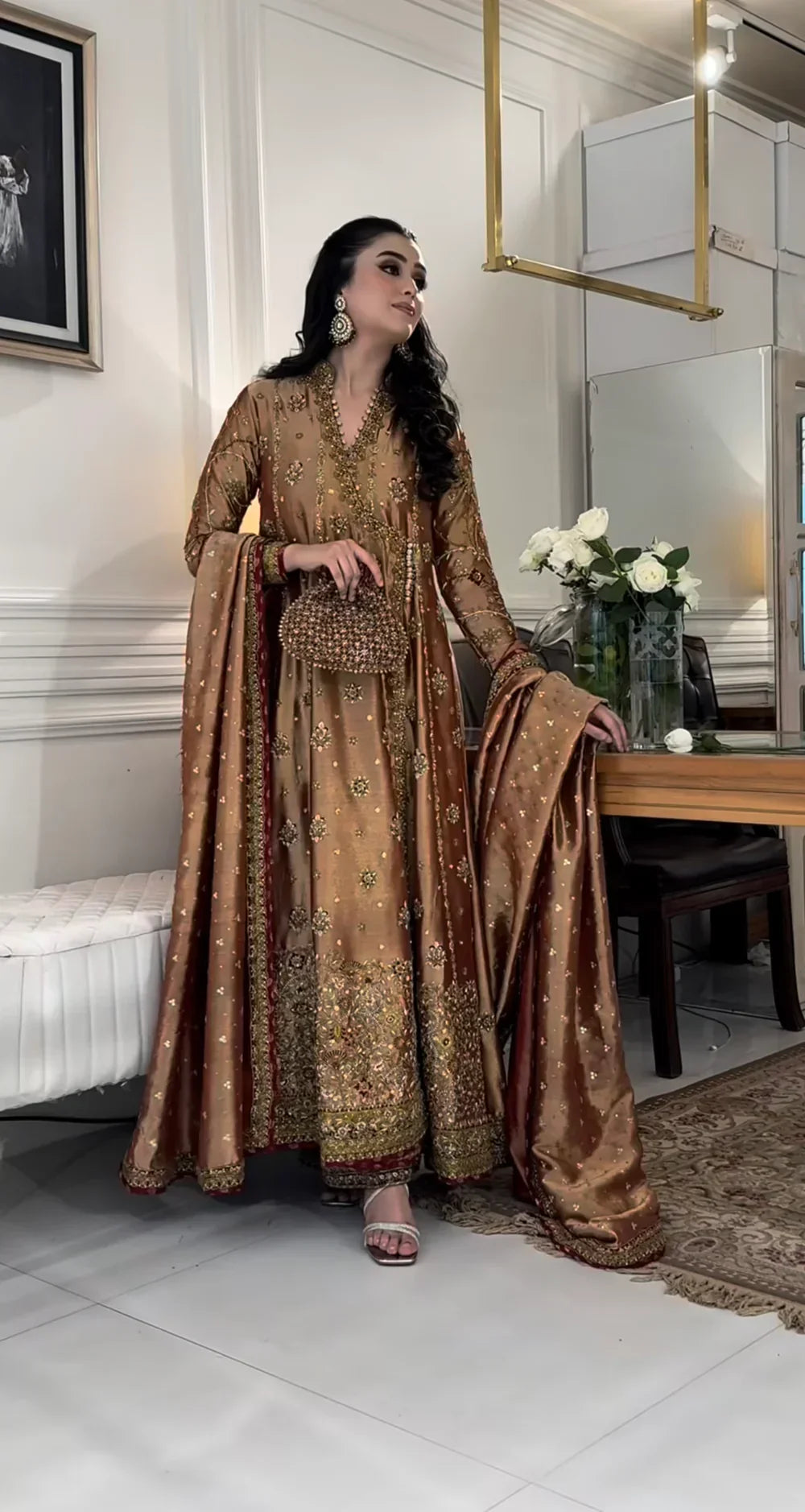Haris Shakeel Aswad bronze-gold formal ensemble featuring intricate hand embellishments with detailed floral motifs, delicate sequins, and refined accents on an elongated silhouette with a heavily worked hemline, perfect for weddings, receptions, formal dinners, and festive celebrations.