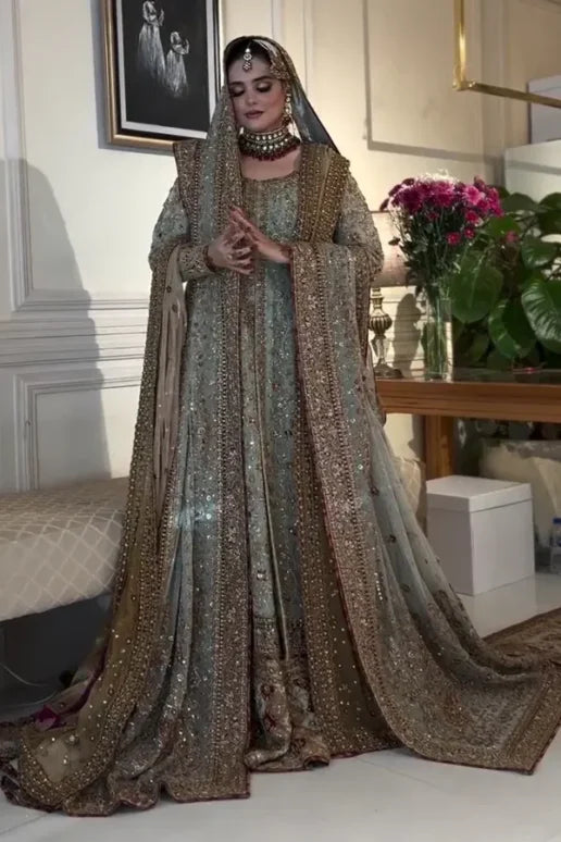 This beautiful ensemble features a richly detailed chiffon kurta adorned with delicate dabka and sitara hand embroidery. The premium malai‑lined kurta provides comfort while enhancing the luxurious feel, and the traditional gharara adds graceful volume and movement to your silhouette