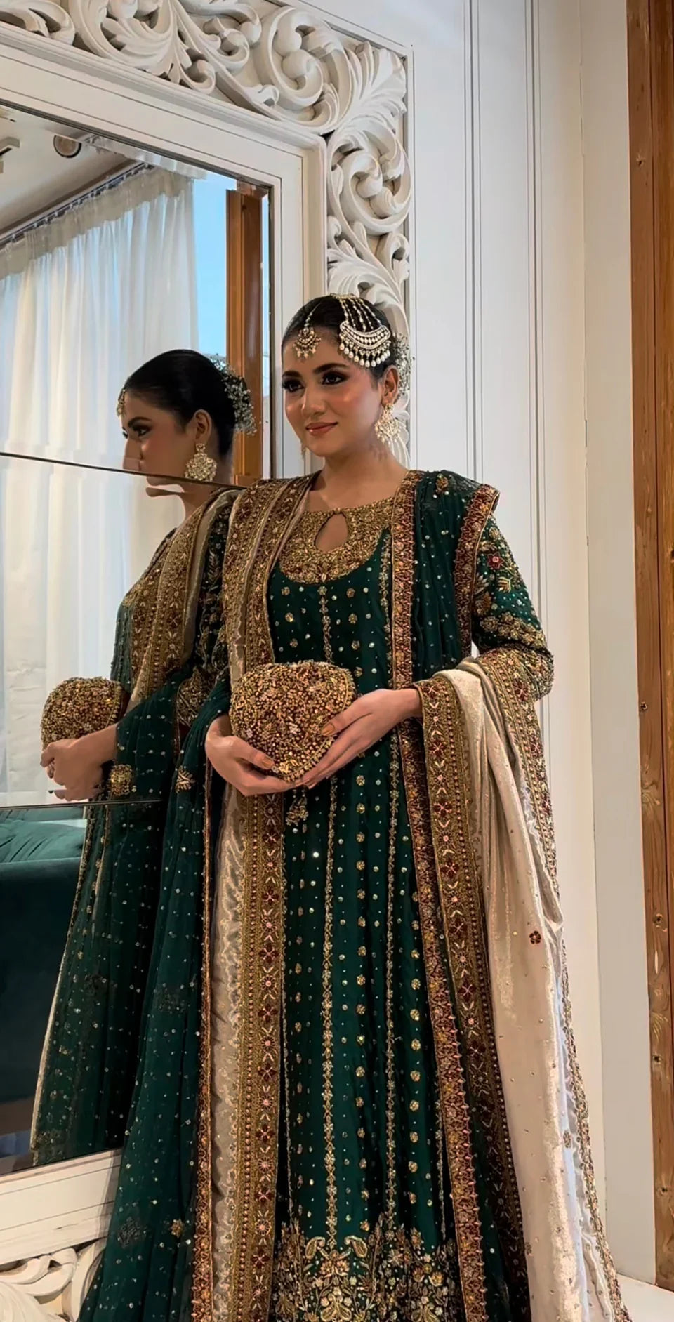  Mehru deep emerald ensemble featuring antique gold and subtle maroon accents with a matching green dupatta edged in ornate red and maroon borders, creating a regal look steeped in timeless tradition and quiet grandeur.