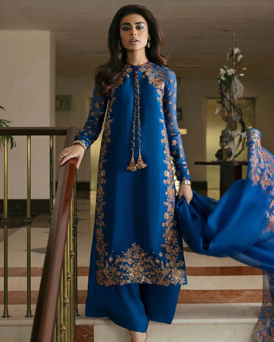 Hussain Rehar Serene teal blue raw silk shirt featuring vibrant screen-printed details with delicate embellishments and chic raglan sleeves in sheer screen-printed organza, paired with plain culottes and a matching screen-printed dupatta, perfect for festive gatherings and semi-formal events.