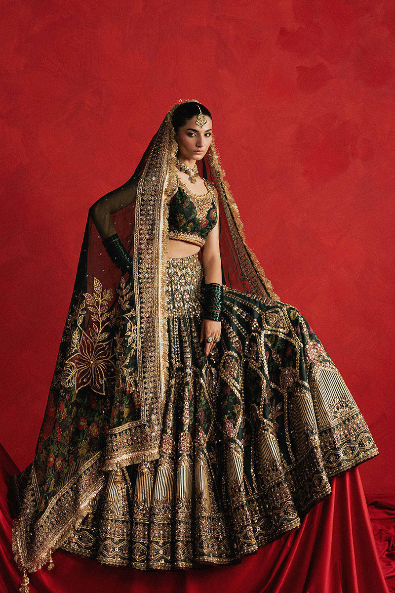 Mohsin Naveed Ranjha Gul-e-Khaas dark green Indian silk lehenga choli featuring a floral printed sleeveless choli with golden embroidery along the neckline and straps, paired with a lehenga layered with appliqués, block-printed motifs, gota patti, mirror work, hand embroidery, and spade-inspired geometric patterns with an ornate golden threadwork hemline, complete with an organza dupatta blooming with printed florals, gota patti, adda work, embroidered borders, kiran trims, and delicate tassels, perfect for